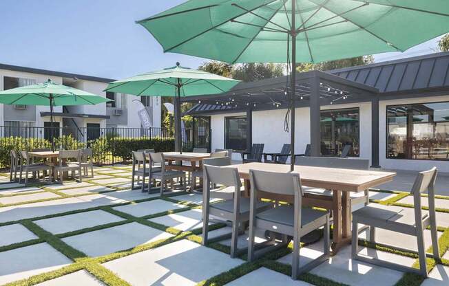 A patio with tables and chairs and umbrellas.