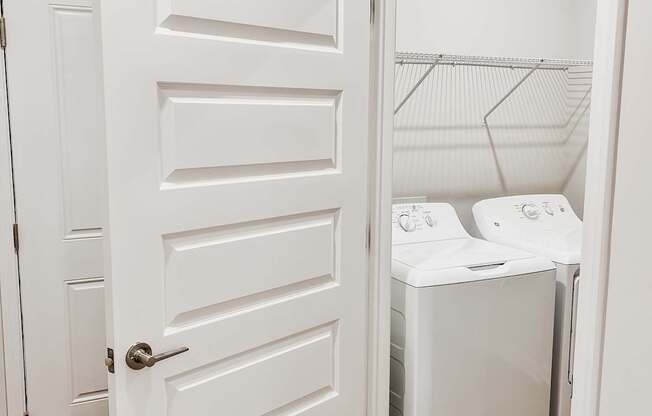 A white door is open to a laundry room with a washer and dryer.
