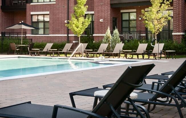 a pool with chaise lounge chairs and a brick building in the background  at The Sheffield Englewood, Englewood, NJ