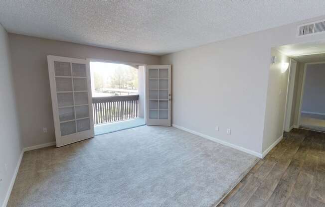 an empty living room with a window and a door to a balcony