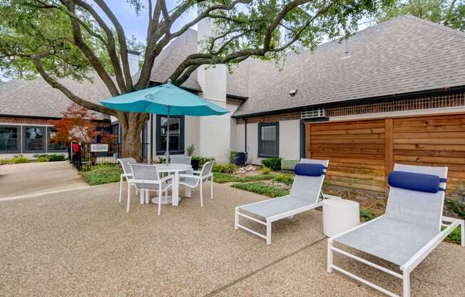 a patio with chairs and an umbrella in front of a house