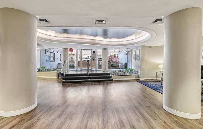 A spacious room with wooden floors and white columns.