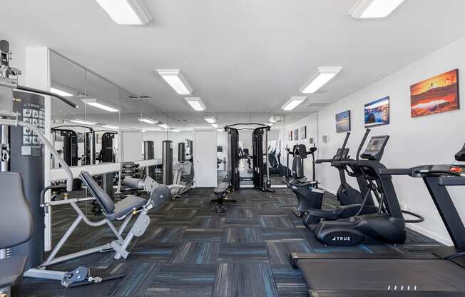A gym with a variety of equipment including treadmills, weights, and exercise machines.
