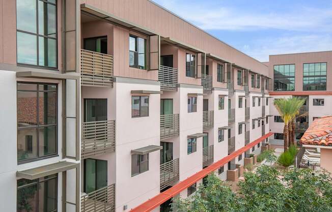 A modern apartment building with balconies and a red roof.