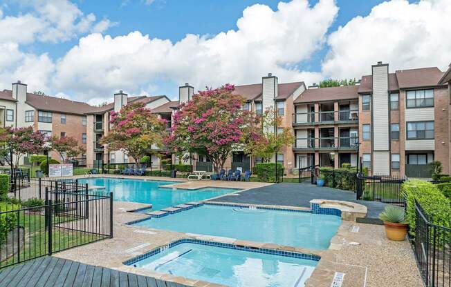 A swimming pool surrounded by a black fence and a building in the background.