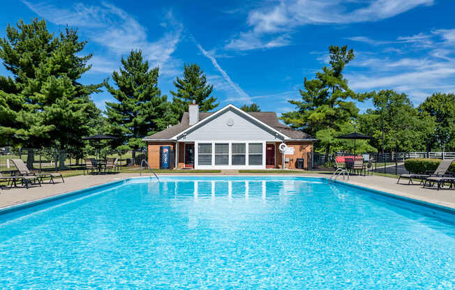 A large swimming pool in front of a building surrounded by trees.