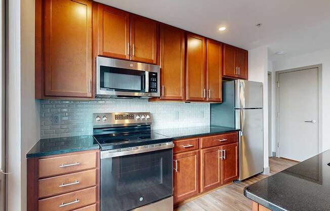 a modern kitchen with brown wooden cabinets, stainless steel appliances, black granite countertops, and a tile backsplash