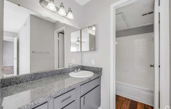 A bathroom with a sink, mirror, and lighting fixture.