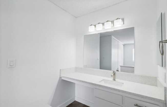 A white bathroom with a sink and mirror.