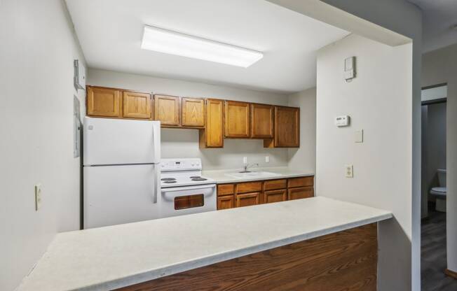 an empty kitchen with white appliances and wooden cabinets
