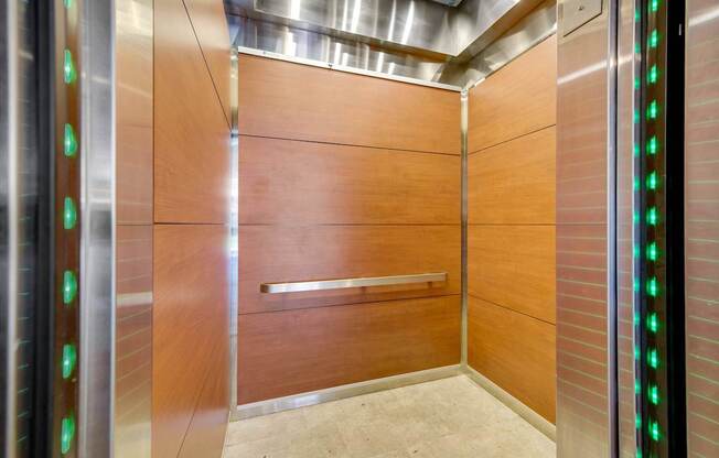 A modern elevator with green lights on the side.