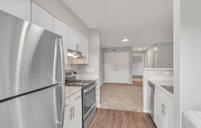 the kitchen and living room of a house with white cabinets and stainless steel appliances