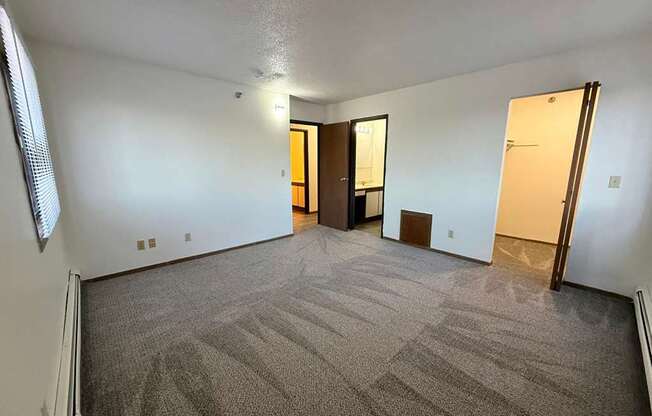 A room with carpeted floor and two doors.