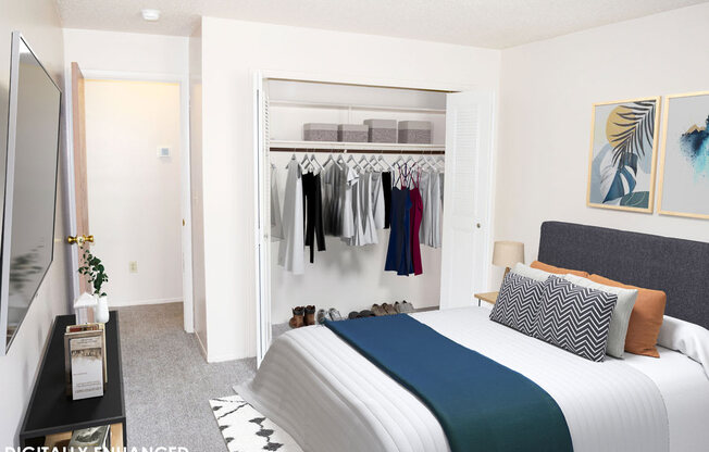 a bedroom with a bed and a closet full of clothes at Seville Apartments, Kalamazoo, MI, 49009