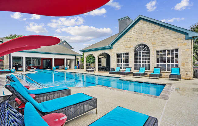 A large swimming pool with lounge chairs and a building in the background.