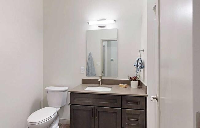 a bathroom with a quartz vanity sink and a mirror with overhead lighting