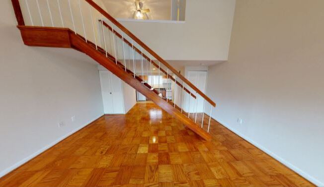 A wooden staircase with a white railing leads up to a second floor.