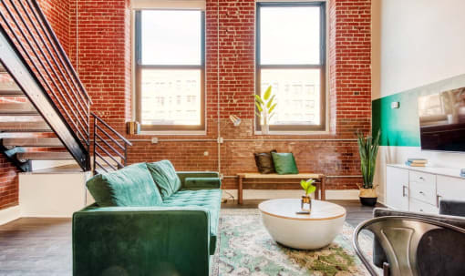 a living room with green furniture and a brick wall