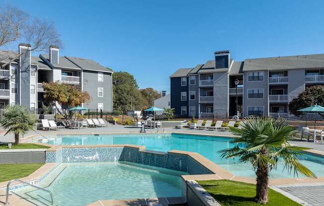 A swimming pool surrounded by a grassy area and apartment buildings.
