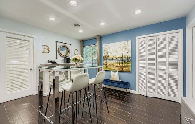 A dining area with a glass table and white chairs.