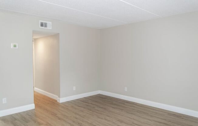 an empty living room with wood flooring and white walls