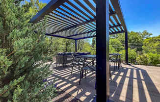 A patio with a table and chairs under a blue and white striped awning.