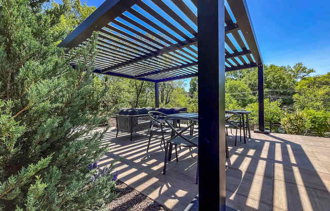 A patio with a table and chairs under a blue and white striped awning.