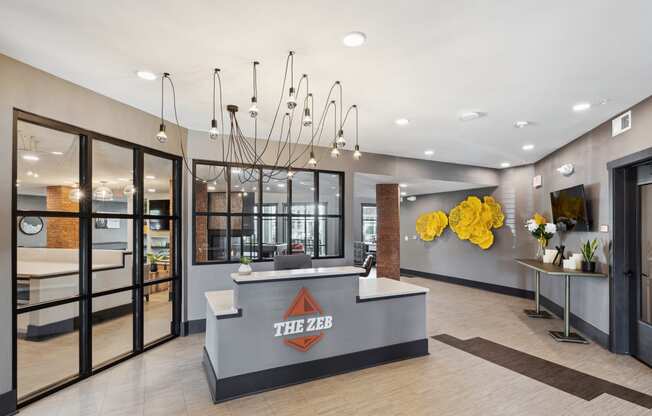 a lobby with a reception desk and a yellow chandelier at The Zeb Apartments