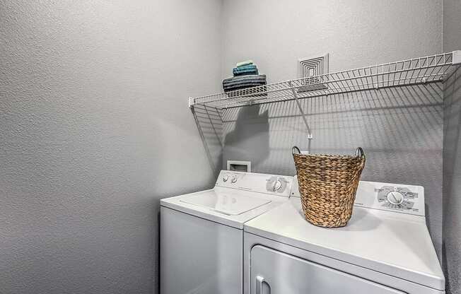 a washer and dryer in a laundry room with a rack on the wall at Mirasol Apartments, Las Vegas, Nevada