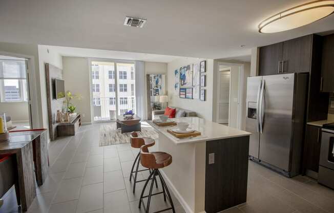 a kitchen and living room with stainless steel appliances and an island with stools