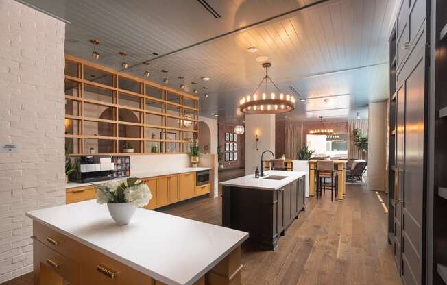 View into the luxurious resident demo kitchen and lounge spaces and dining area of a modern home with wood floors and white countertops at Sylvan Uptown, Colorado, Denver