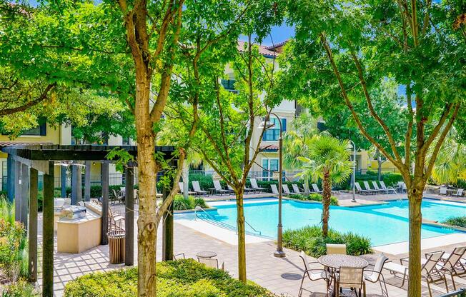 Sparkling pool surrounded by trees at Mission at La Villita Apartments in Irving, TX offers 1, 2 & 3 bedroom apartment homes with appliances.