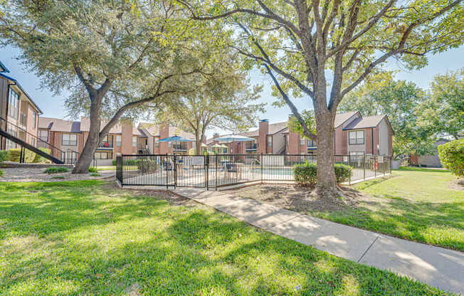 A tree in front of a building with a fence around it.