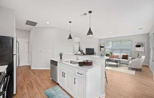 a white kitchen with an island and a living room