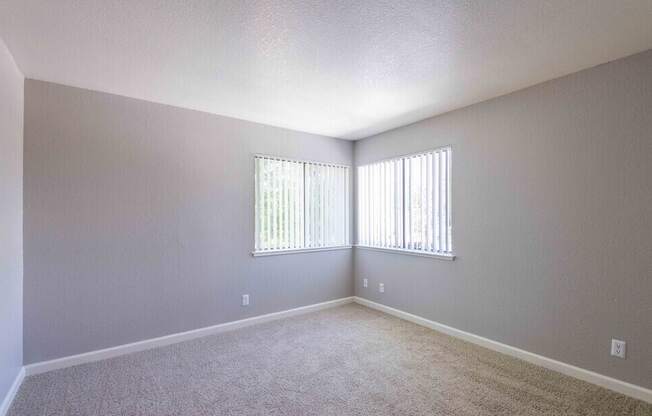 A room with a carpeted floor and a window with blinds.