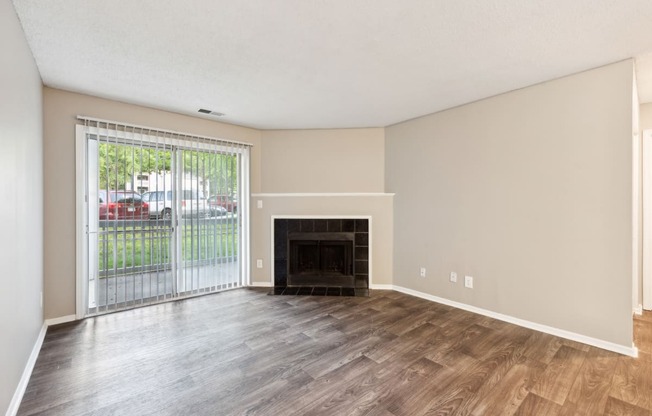 an empty living room with a fireplace and a sliding glass door