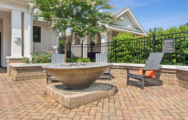 a fountain sits on a brick patio in front of a house