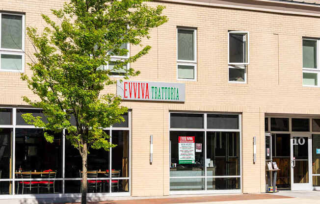 A building with a tree in front of it and a sign that says EVVIVIA TRATORIA.