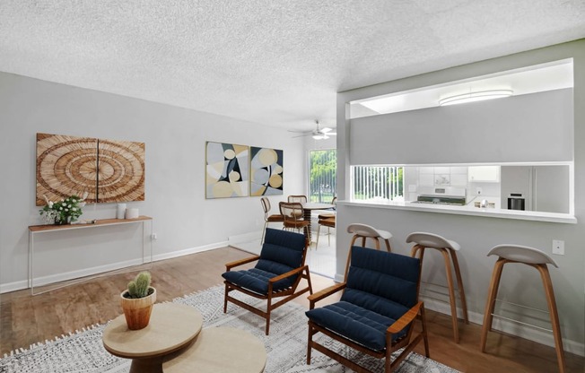 a living room with chairs and a bar and a kitchen