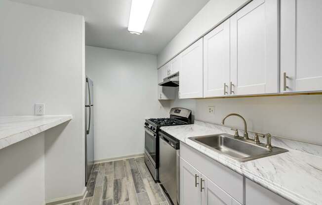A renovated kitchen with a white refrigerator, a stove, a dishwasher, and a sink.