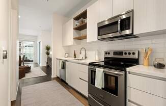 A modern kitchen with a black stove top oven and white cabinets.