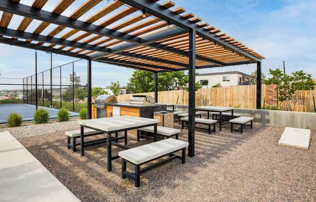 a patio with tables and benches and a barbecue grill