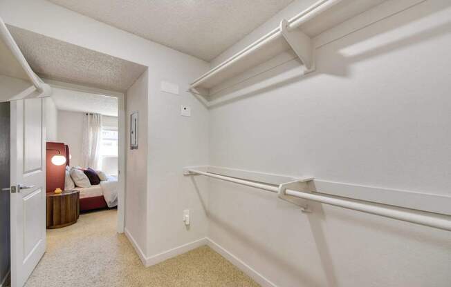 A white bedroom with a bed and a nightstand with a lamp.