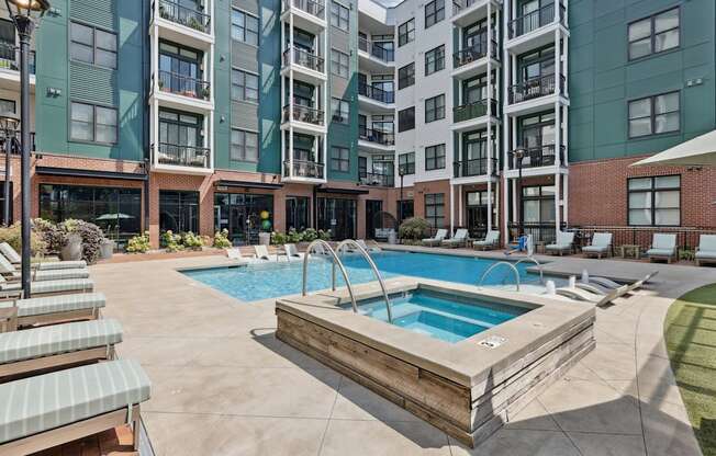 A large outdoor swimming pool with a wooden deck and lounge chairs.