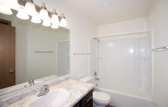 a bathroom with a sink and a shower and a toilet. Fargo, ND Country Club Apartments