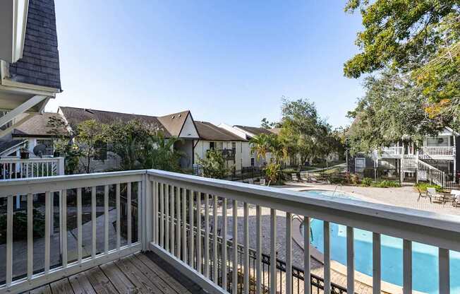 A view from a balcony overlooking a pool and houses.