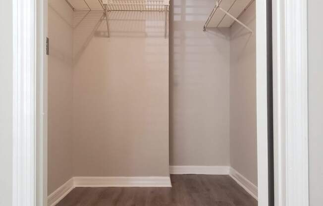 a spacious closet with shelves and a wood floor in an empty room