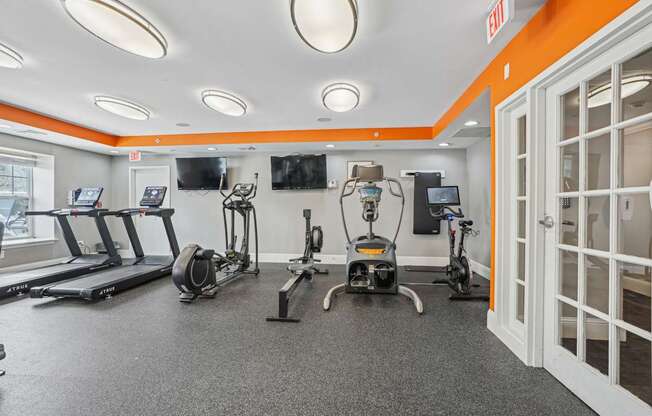 A gym with orange walls and a variety of exercise equipment.