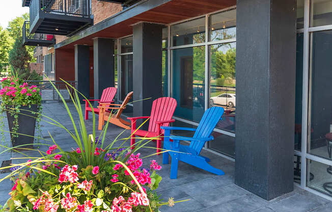 A patio with red and blue chairs and a flower bed.