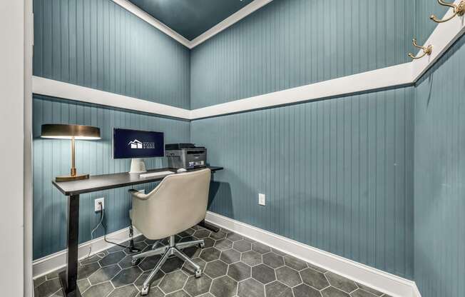 a home office with blue wallpaper and a desk with a computer